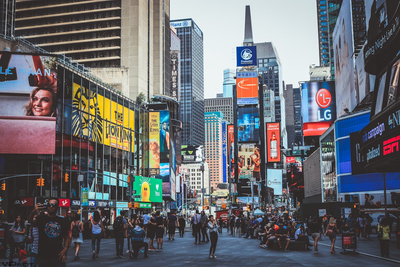 about-01 Bustling daytime view of Times Square with crowds, skyscrapers, and iconic billboards in New York City.