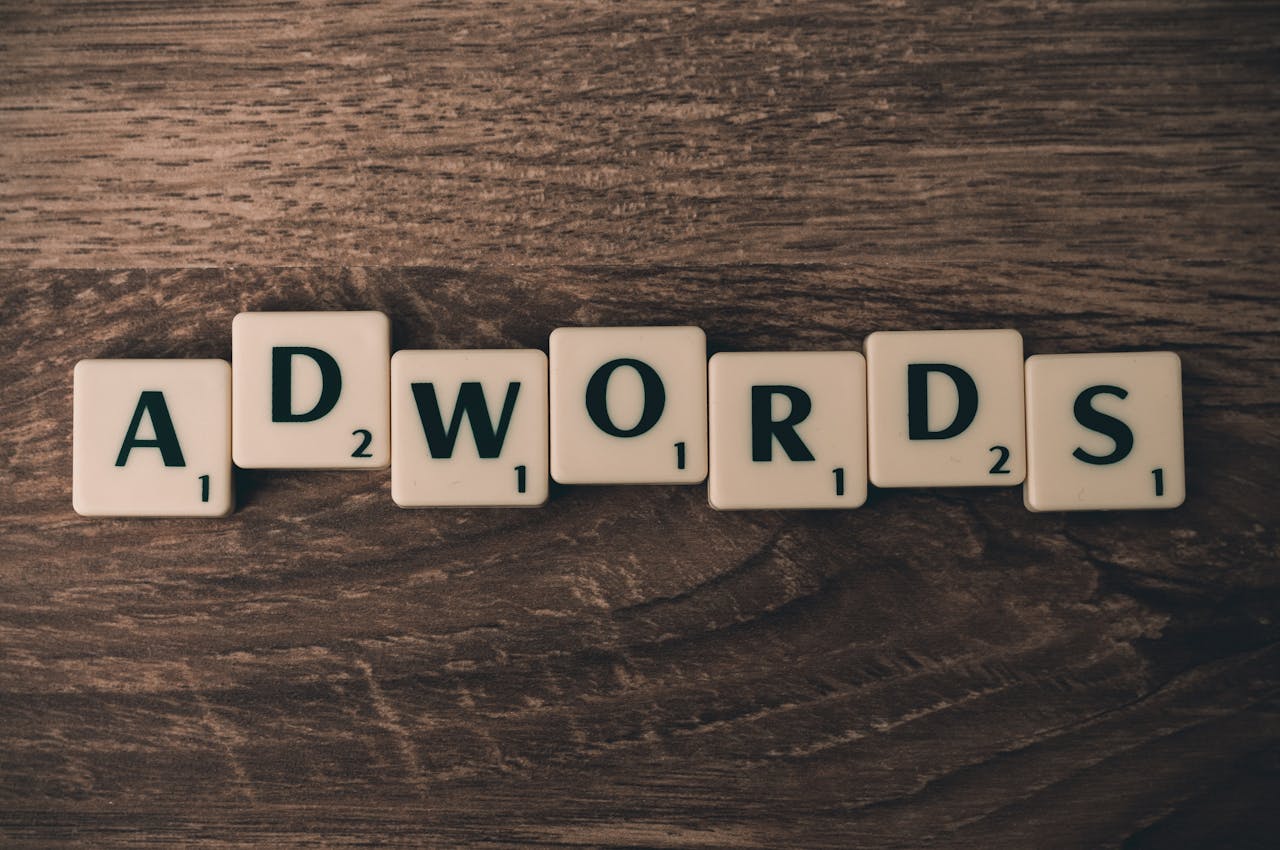 ours-journey Scrabble tiles spelling 'AdWords' on a wooden surface, symbolizing digital marketing concepts.